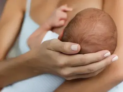 Młoda kobieta karmiąca piersią swoje nowo narodzone dziecko w domu